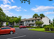 Thumbnail 24 of 26 - A red car is parked in a parking lot in front of a building.