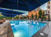 Thumbnail 37 of 58 - a swimming pool with lounge chairs and umbrellas in front of a building