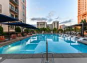 Thumbnail 38 of 58 - Luxury Apartments in Buckhead, GA, with In-Unit Washer and Dryer - 92 West Paces - Saltwater Pool with Submerged and Poolside Lounge Seats, Blue Umbrellas, Gazebos, Chairs, and Urban Views.
