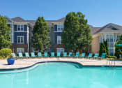 Thumbnail 37 of 59 - Chapel Hill, NC, Luxury Apartments with In-Unit Washers and Dryers - The Reserve at Meadowmont - Resort-Style Swimming Pool with Sundeck, Lounge Chairs, Surrounding Trees, and Apartment Buildings in the Background.