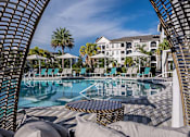 Thumbnail 40 of 54 - A pool surrounded by lounge chairs and umbrellas with a building in the background.