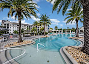 Thumbnail 42 of 54 - A pool surrounded by palm trees and a resort.