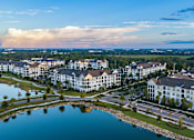 Thumbnail 53 of 54 - A large white building complex is surrounded by a lake and greenery.
