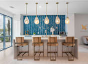 Thumbnail 5 of 29 - Sarasota, FL Luxury Apartments With In-Unit Washer And Dryer - Botanic Waterside - Community Kitchen With Window Wall, Blue Backsplash, Counter Seating, And Pendant Lights.