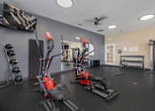 Thumbnail 17 of 22 - A gym with a variety of equipment including treadmills, weights, and a television.