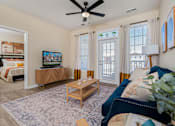 Thumbnail 1 of 22 - A living room with a ceiling fan and a television.