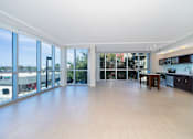 Thumbnail 31 of 39 - Orlando, FL, Luxury Apartments Near Lake Eola Park - NORA - An Empty Open-Concept Living Area with Wood-Style Flooring, Floor-to-Ceiling Windows with Roll-Up Blinds, and Adjacent to the Kitchen.