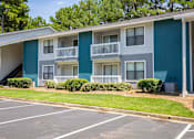 Thumbnail 29 of 30 - A blue and white apartment building with a parking lot in front.