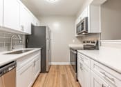 Thumbnail 5 of 30 - A kitchen with white cabinets and a black refrigerator.