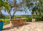 Thumbnail 21 of 34 - a patio with a grill and a table with chairs and an umbrella at L'Estancia, Sarasota, FL