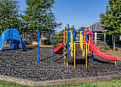 Thumbnail 21 of 29 - A playground with a blue and yellow slide and a red slide.