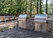 Thumbnail 28 of 35 - Three outdoor grills are lined up on a gravel area.