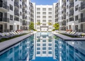 Thumbnail 1 of 22 - an outdoor pool with lounge chairs and a white building in the background at Leena Plantation, Florida, 33322