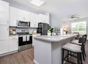 Thumbnail 9 of 24 - A kitchen with a white island and a black refrigerator.