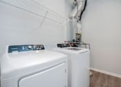 Thumbnail 23 of 24 - A white washing machine and dryer in a small laundry room.