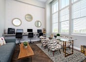 Thumbnail 6 of 24 - A modern living room with a grey couch, a glass table, and a patterned chair.