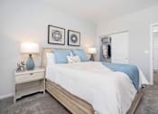 Thumbnail 19 of 24 - A bedroom with a bed, nightstand, and two wall art pieces.