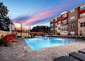 Thumbnail 35 of 46 - an outdoor swimming pool at dusk with an apartment building in the background
