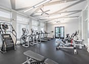 Thumbnail 21 of 41 - A spacious gym with a variety of equipment including treadmills, stationary bikes, and weight machines.