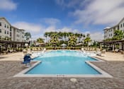 Thumbnail 27 of 41 - A large swimming pool surrounded by a brick patio and lounge chairs.