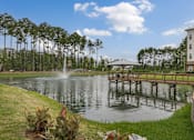 Thumbnail 34 of 41 - A fountain in the middle of a lake with a bridge in the background.
