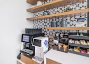 Thumbnail 12 of 47 - A white and black checkered tile backsplash behind a counter with a cash register and a digital menu.