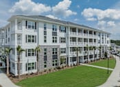Thumbnail 39 of 47 - A white building with balconies and a green lawn in front.