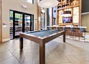 Thumbnail 23 of 36 - A pool table in a room with a television and a bar.