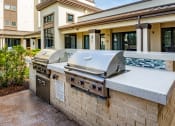Thumbnail 28 of 35 - a large stainless steel grill sits on a stone counter outside of a building