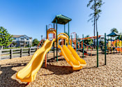 Thumbnail 4 of 24 - A playground with a yellow slide and a green roofed structure.