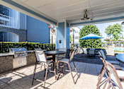 Thumbnail 3 of 24 - Luxury Apartments In Greenville, SC With In-Unit Washer And Dryer - The Aventine Greenville - A Covered Outdoor Grilling Station With A Stainless Steel Grill, Stone Masonry, And Patio Dining Tables.