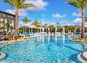 Thumbnail 1 of 29 - Luxury Apartments in Sarasota, FL With In-Unit Washer And Dryer - Botanic Waterside - Resort-Style Swimming Pool With Spacious Sundeck, Lounge Chairs, Umbrellas, Cabanas, And Palm Trees.
