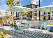 Thumbnail 14 of 29 - A patio with white furniture and green umbrellas.