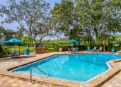 Thumbnail 20 of 34 - a resort style pool with chairs and umbrellas and trees at L'Estancia, Sarasota, FL
