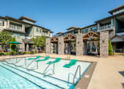 Thumbnail 16 of 37 - the preserve at ballantyne commons pool with lounge chairs and apartment buildings