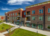 Thumbnail 1 of 32 - Mt. Juliet, TN Apartments for Rent - The Enclave at Providence - Street View of Property with Manicured Grass Lawn and Wide Concrete Walkway.