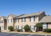 Thumbnail 16 of 16 - Atlanta, GA Apartments - City Park - Exterior of Apartments with Manicured Bushes, Walking Path, and Parking Lot.