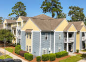 Thumbnail 30 of 31 - an apartment building with blue and yellow siding and a parking lot