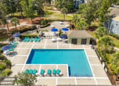 Thumbnail 29 of 31 - a swimming pool with chairs and umbrellas in front of a house