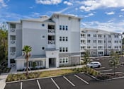 Thumbnail 31 of 31 - A white apartment building with a parking lot in front.