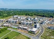 Thumbnail 14 of 14 - A bird's eye view of a large, modern residential complex surrounded by greenery.