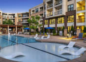 Thumbnail 44 of 49 - a swimming pool with lounge chairs in front of an apartment building