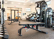 Thumbnail 21 of 35 - A gym with a variety of equipment including weights and cardio machines.
