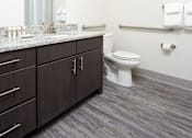 Thumbnail 19 of 25 - A bathroom with a toilet, sink, and mirror.