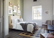 Thumbnail 14 of 25 - A bedroom with a large bed and a chair.