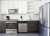 Thumbnail 10 of 25 - A modern kitchen with a stainless steel refrigerator and a white tile backsplash.