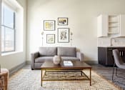 Thumbnail 12 of 25 - A living room with a grey couch, a coffee table, and a chair.