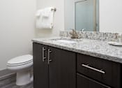 Thumbnail 16 of 25 - A bathroom with a toilet, sink, and mirror.