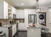Thumbnail 24 of 46 - A modern kitchen with white cabinets and stainless steel appliances.