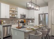 Thumbnail 25 of 46 - A kitchen with a granite countertop and stainless steel appliances.
